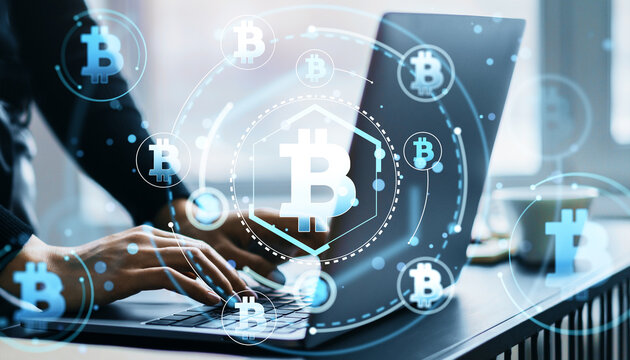 Person working on laptop with Bitcoin hologram icons.