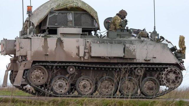 commander directing a British army Bulldog FV432 tank along a dirt road