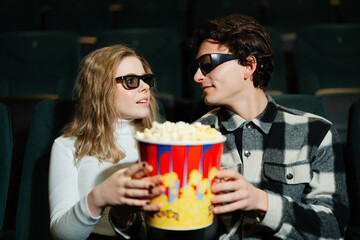 Couple enjoying popcorn and a movie in a theater with 3D glasses