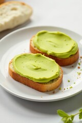 Elegant white plate displays artisan bread with smooth pistachio spread, light backdrop , foodie, artisan bread
