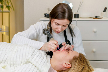 girl permanent makeup artist doing permanent lip makeup to middle aged woman