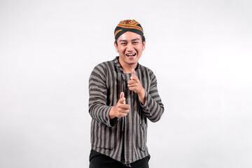 A cheerful Indonesian man dressed in traditional Javanese clothing, wearing a striped lurik sorjan...