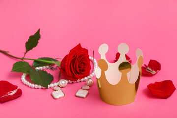 Paper crown with jewelry and beautiful rose on pink background. Prom concept