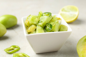 Delicious salsa (Pico de gallo) in bowl and products on light textured table, closeup