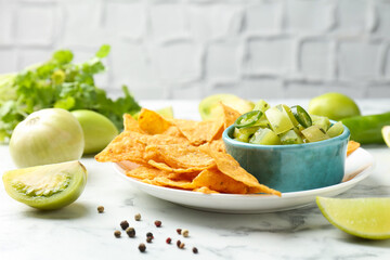 Delicious salsa with nachos on white marble table, closeup