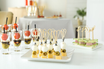 Many different tasty canapes on white table indoors