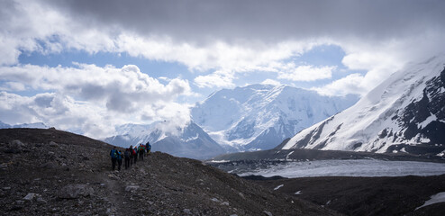 Group of hikers walking through alpine glacier landscape in Pamir Mountains, Kyrgyzstan