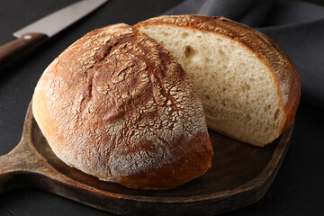 Cut loaf of bread on black table, closeup