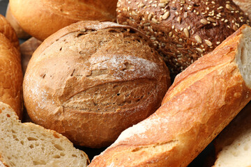 Whole and cut loafs of bread on table, closeup