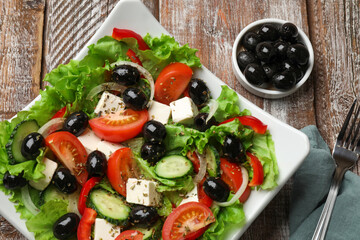 Delicious fresh Greek salad on wooden table, top view