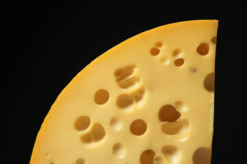 Piece of tasty cheese on black background, closeup