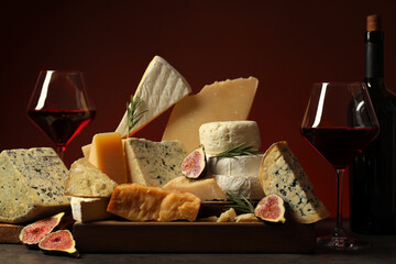 Different types of cheese, rosemary, figs and wine on table