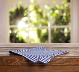 Blue checkered tablecloth on wooden table in room, closeup