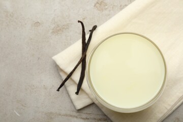 Glass of milk and vanilla pods on light grey table, flat lay. Space for text