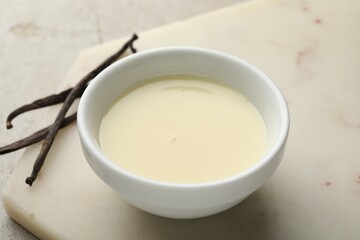 Tasty condensed milk and vanilla pods on light grey table, closeup