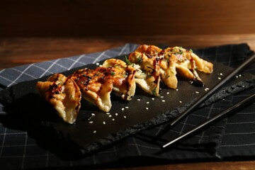 Tasty fried gyoza (dumplings) and chopsticks on wooden table, closeup