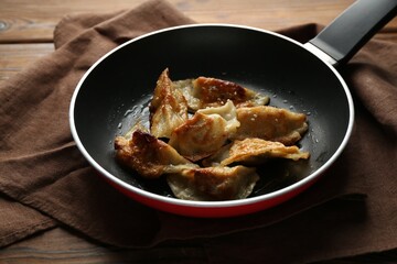 Tasty fried gyoza (dumplings) on wooden table, closeup