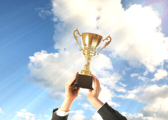 Man holding golden trophy against sky, closeup