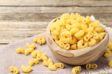Raw horns pasta in bowl on table, closeup. Space for text