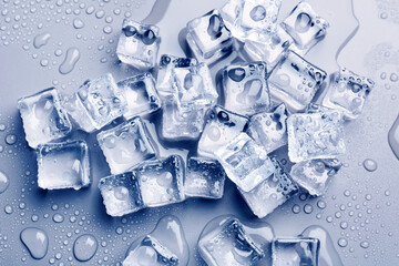 Ice cubes and water drops on light blue background, flat lay