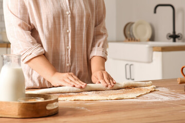 Woman preparing traditional cinnamon rolls in kitchen