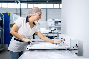 Fototapeta premium Professional dry cleaning worker packing clean folded laundry for customer.