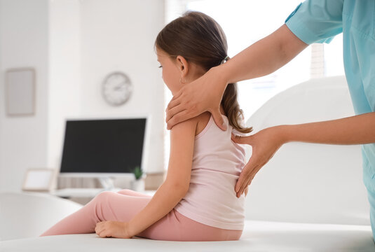 Female osteopath working with little patient in clinic, back view
