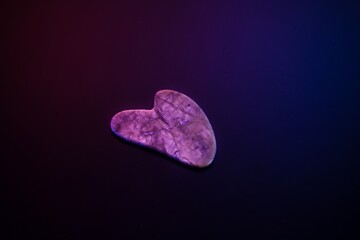 Gua Sha Facial Stone on Black Background with Neon Lighting

