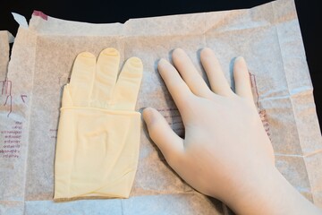 Gloved Hand and Sterile Surgical Glove on Packaging Paper