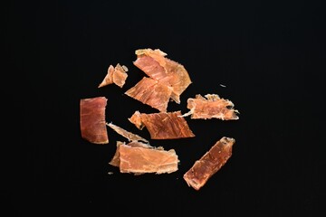 Dried Meat Jerky Pieces on Black Background – Protein Snack or Paleo Concept
