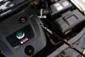 Checking Engine Oil Level with Dipstick in Car Engine Bay


