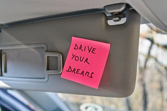 Sticky note with 'Drive Your Dreams' on car sun visor