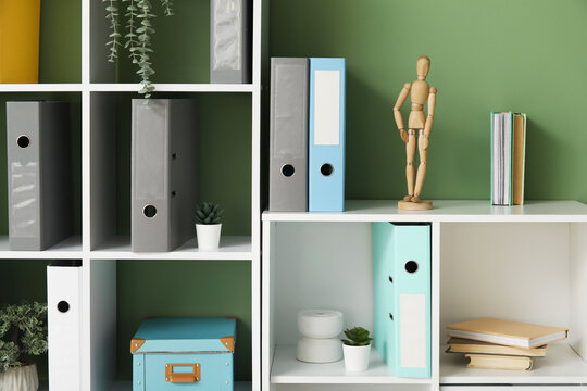 Shelf units with document folders and plants near green wall