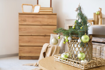 Small Christmas tree with baubles on coffee table in festive living room