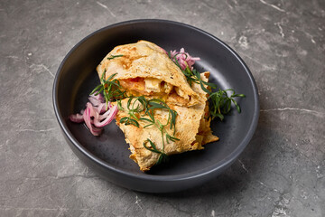 Delicious cheesy quesadilla with fresh herbs and onions served on dark plate, stone background,...