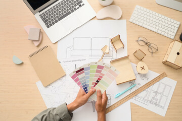Male furniture designer with color palettes on table, top view