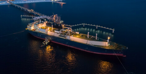 A large LNG tanker docks at an industrial port terminal for cargo operations at dusk