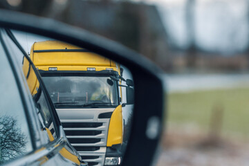 Reflection in the side mirror of a passenger car of a truck approaching too closely