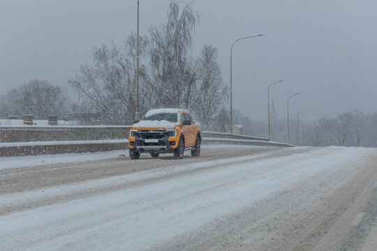 Snow covered car on snow covered road during snowfall.