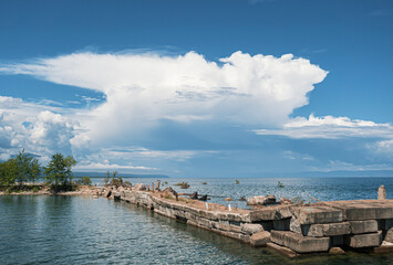 Obraz premium Clouds loom over a tranquil lakeside pier in a serene afternoon landscape