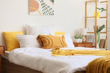 Cozy bed with soft pillows, blanket and bedside table in bedroom