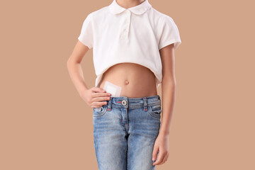 Teenage girl with applied medical patch after appendectomy surgery on beige background