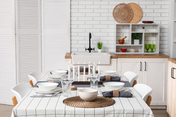 Festive table setting with burning candles in kitchen