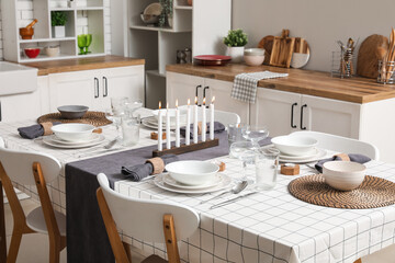 Festive table setting with burning candles in kitchen. Closeup