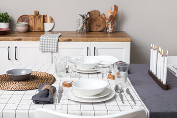 Beautiful table setting with burning candles in kitchen. Closeup
