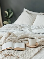 Coffee cup and book placed on bed and blanket