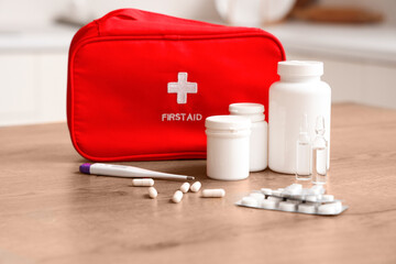 Pills, bottles of medicine and first aid kit on table at home, closeup
