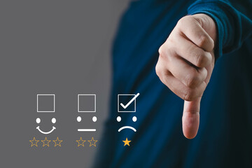 Conceptual image of customer dissatisfaction with a thumbs-down gesture and a sad rating. Perfect...