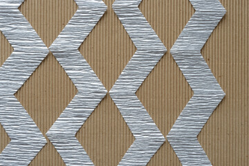 metallic silver crepe paper stripes with zigzag edges on corrugated plain cardboard background