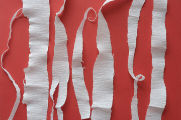 torn white crepe paper stripes and strands on red